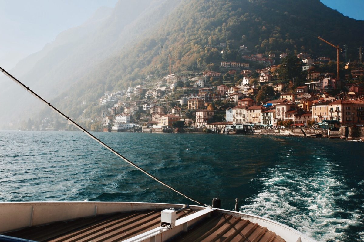 boat on a lake with villas and mountains in the distance