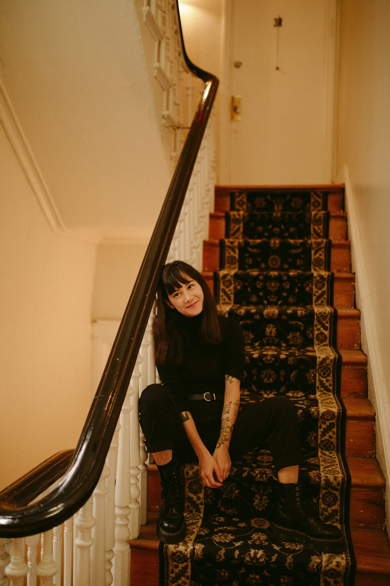 a girl sits at the bottom of a flight of stairs