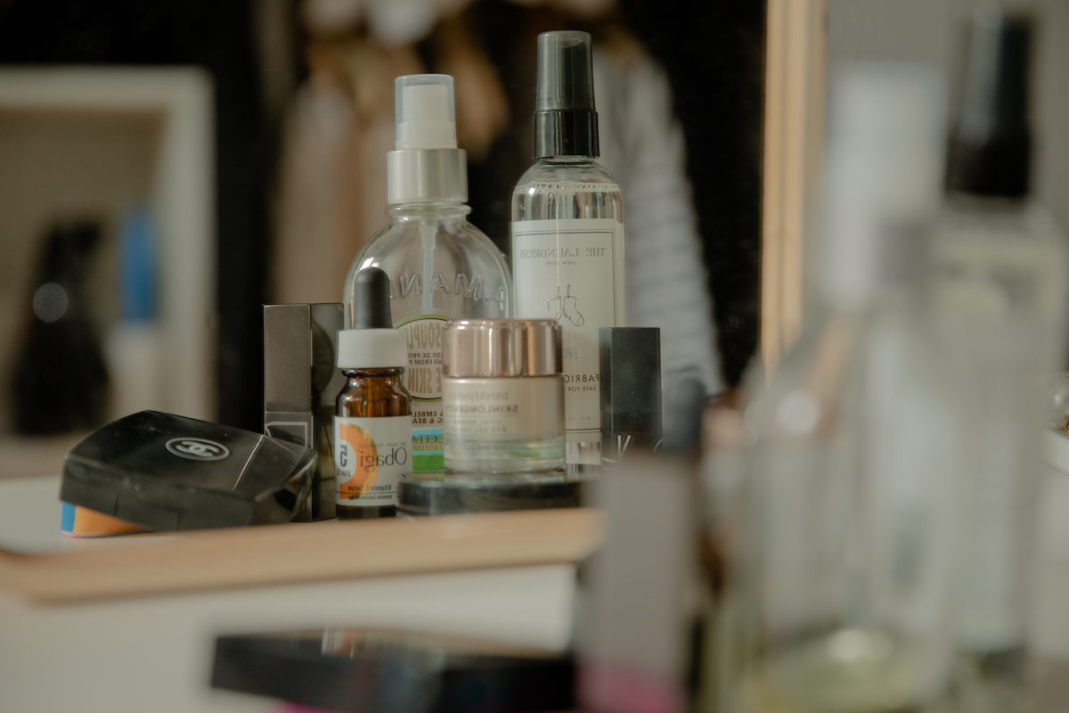 beauty products on a vanity counter reflected in a mirror