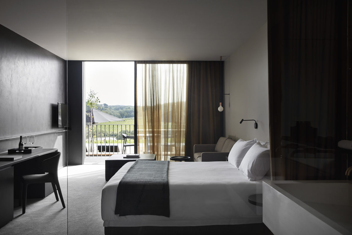 A bed inside a hotel room with a view of the Jackalope's vineyard beyond.