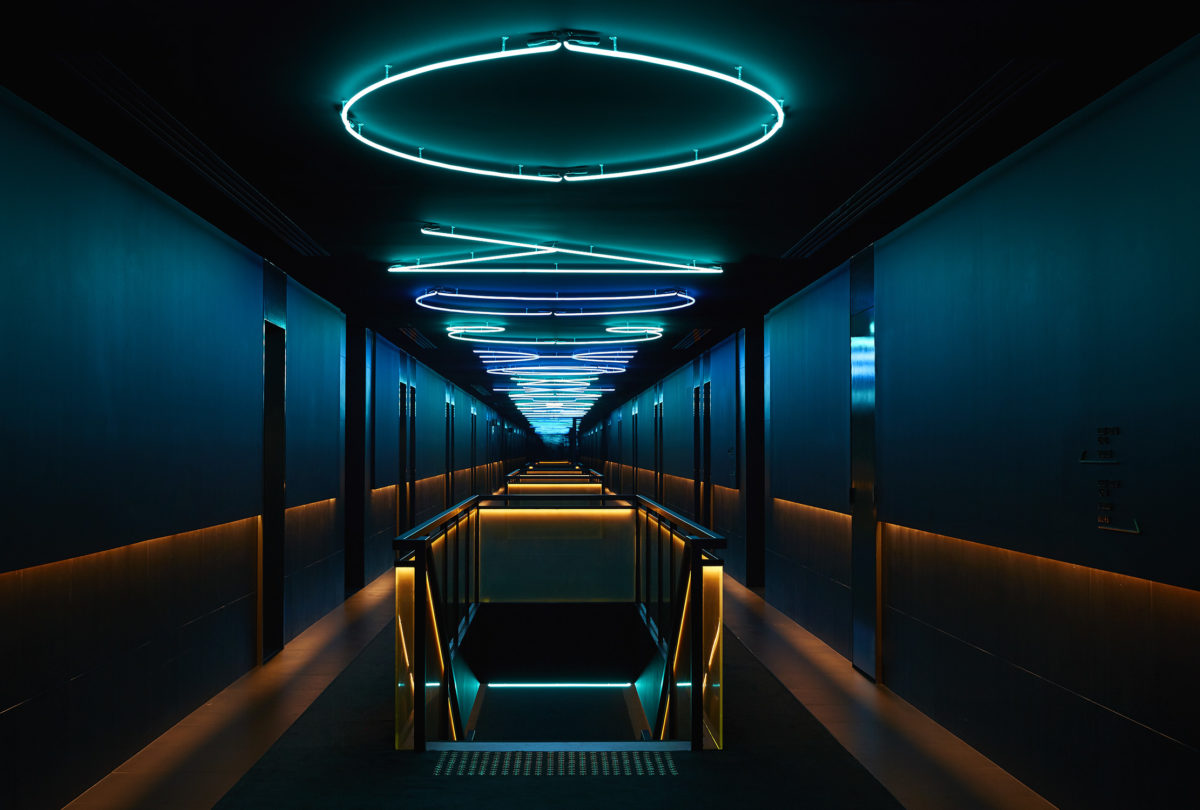 A dark hallway in the Jackalope lit up by neon shapes on the ceiling.