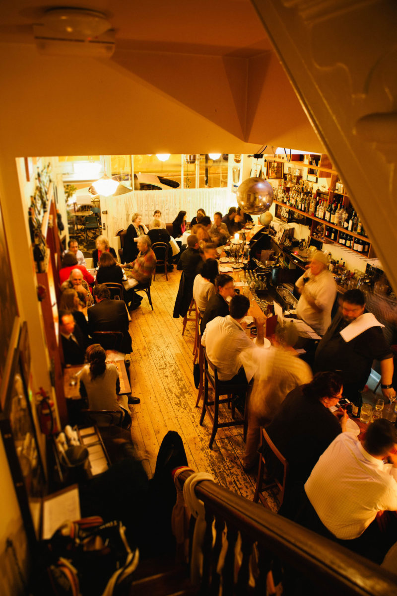 A crowd of people inside a golden-lit bar.