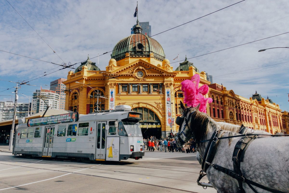 A railway car and a horse pass in front of a giant golden building with a gray dome.