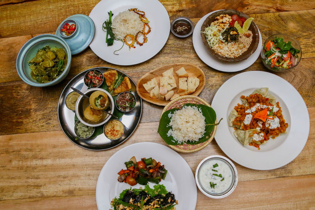 top view photo of a wooden table with several plates of asian fusion cuisine