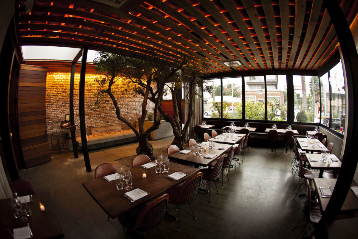 a dimly lit, dark wood dining room with large open windows and small light fixtures dotting the ceiling