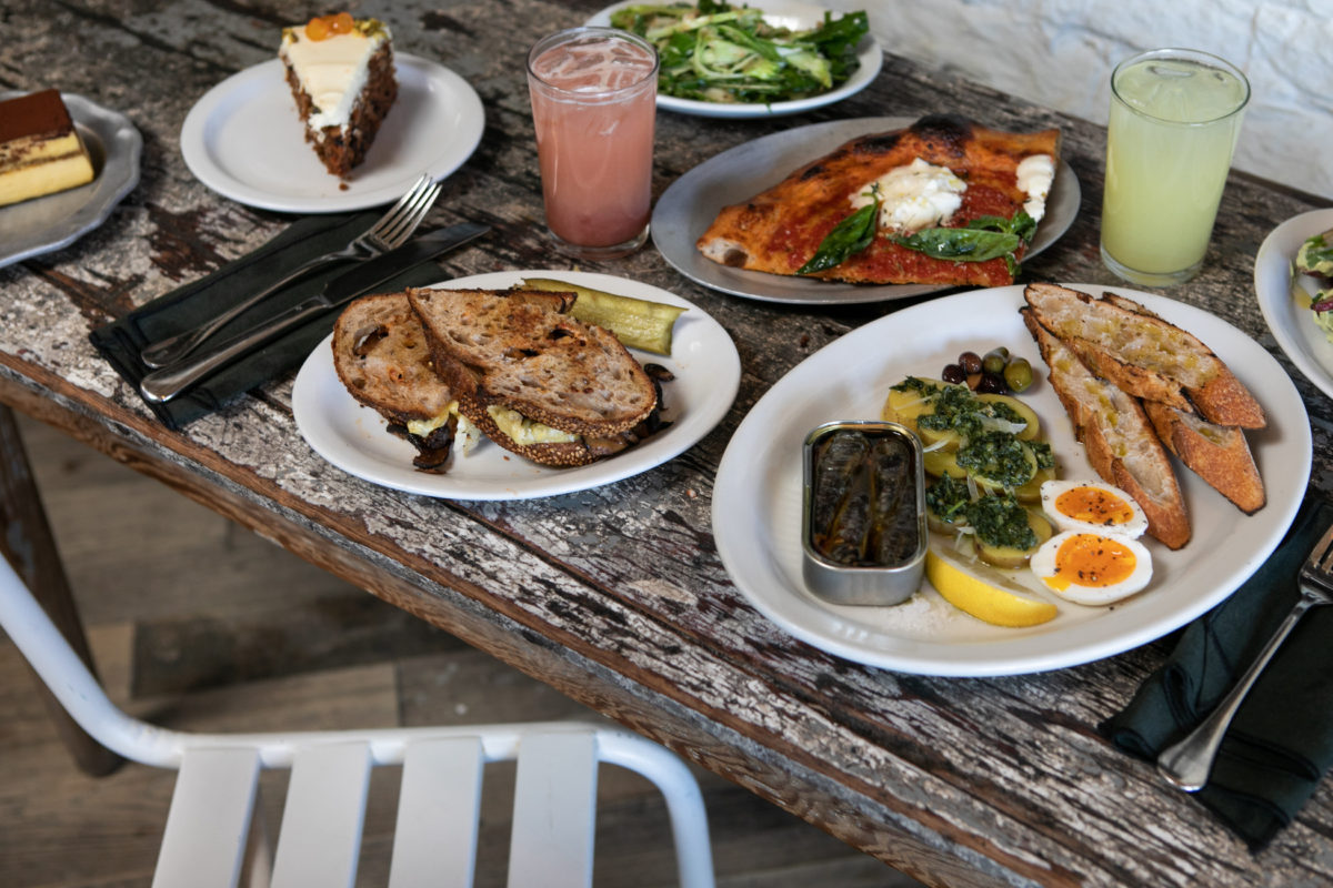 a white chair sits against a gray wood table filled with a variety of foods and drinks