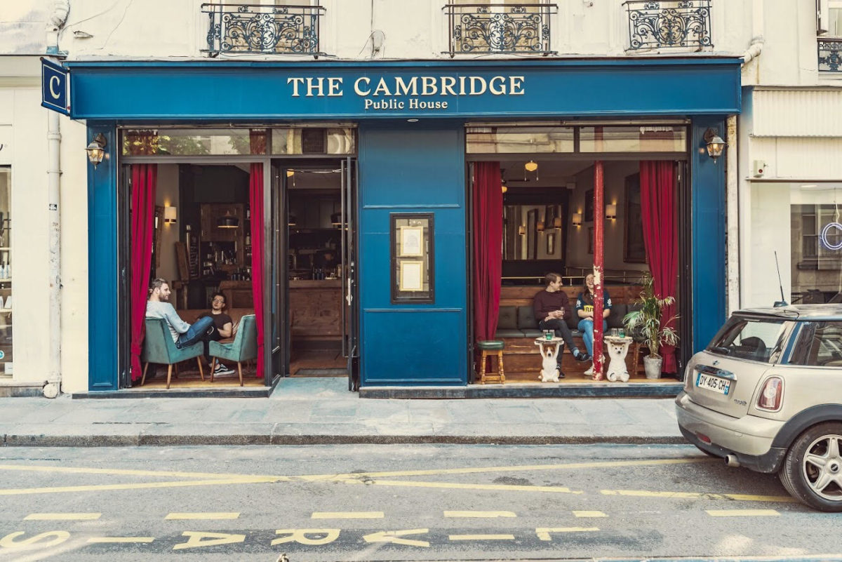 the facade of a pub called "The Cambridge" with a deep turquoise exterior and red curtains