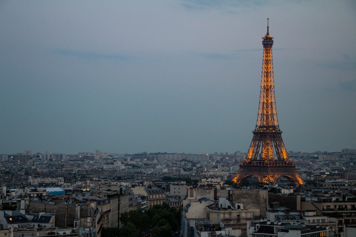 a overcast sky over Paris with the lit-up Eiffel Tower in the distance