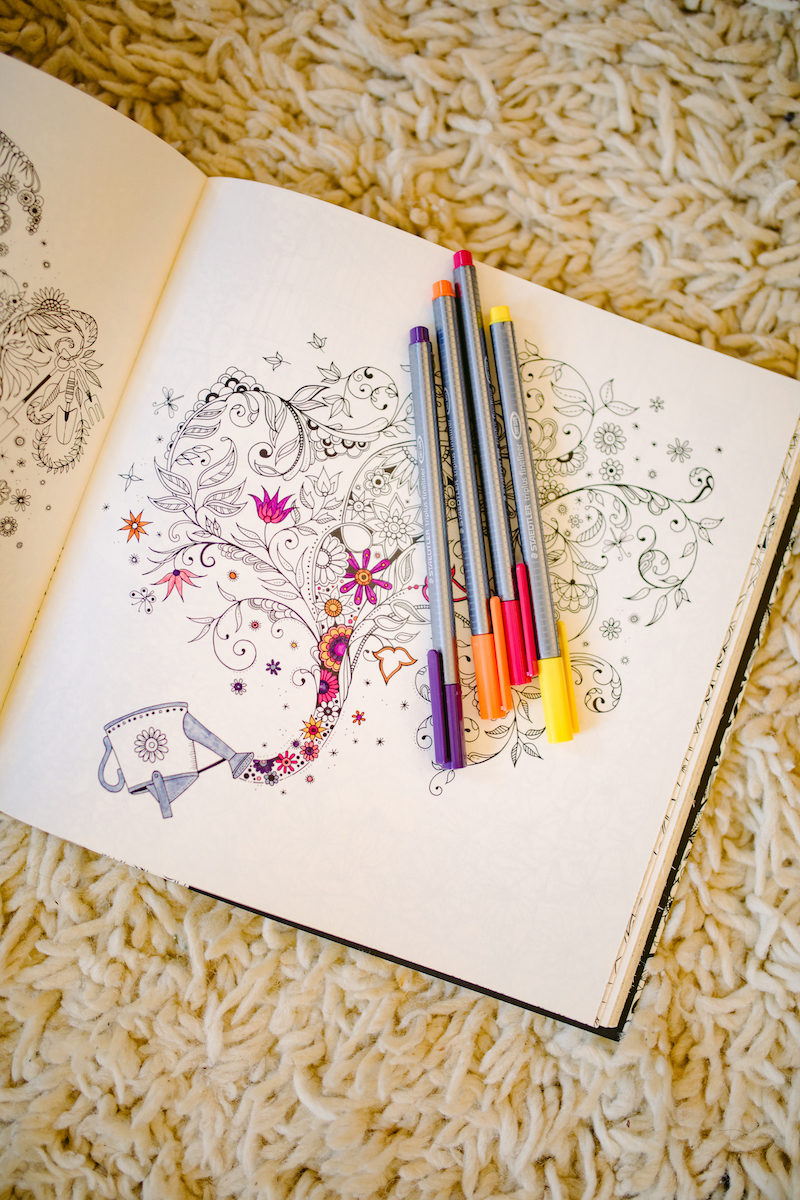 a half-filled coloring book page with pens