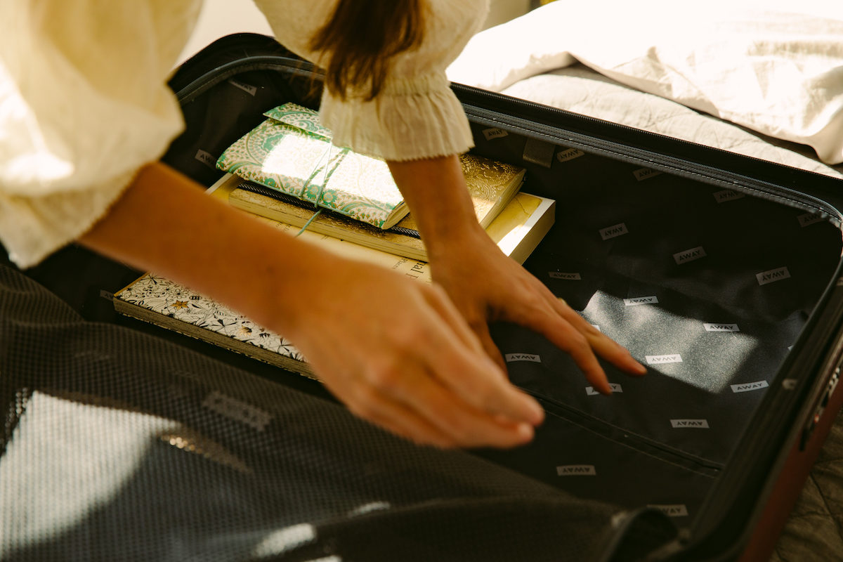 a pair of woman's hands move things around in a suitcase