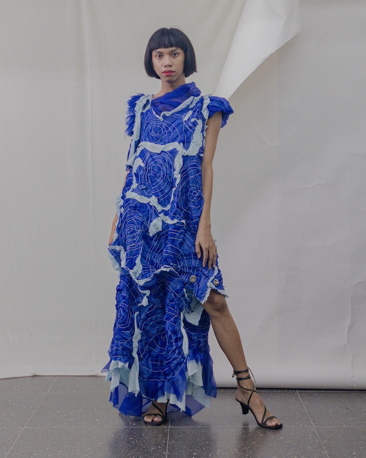 a woman with short black hair wearing a long blue dress