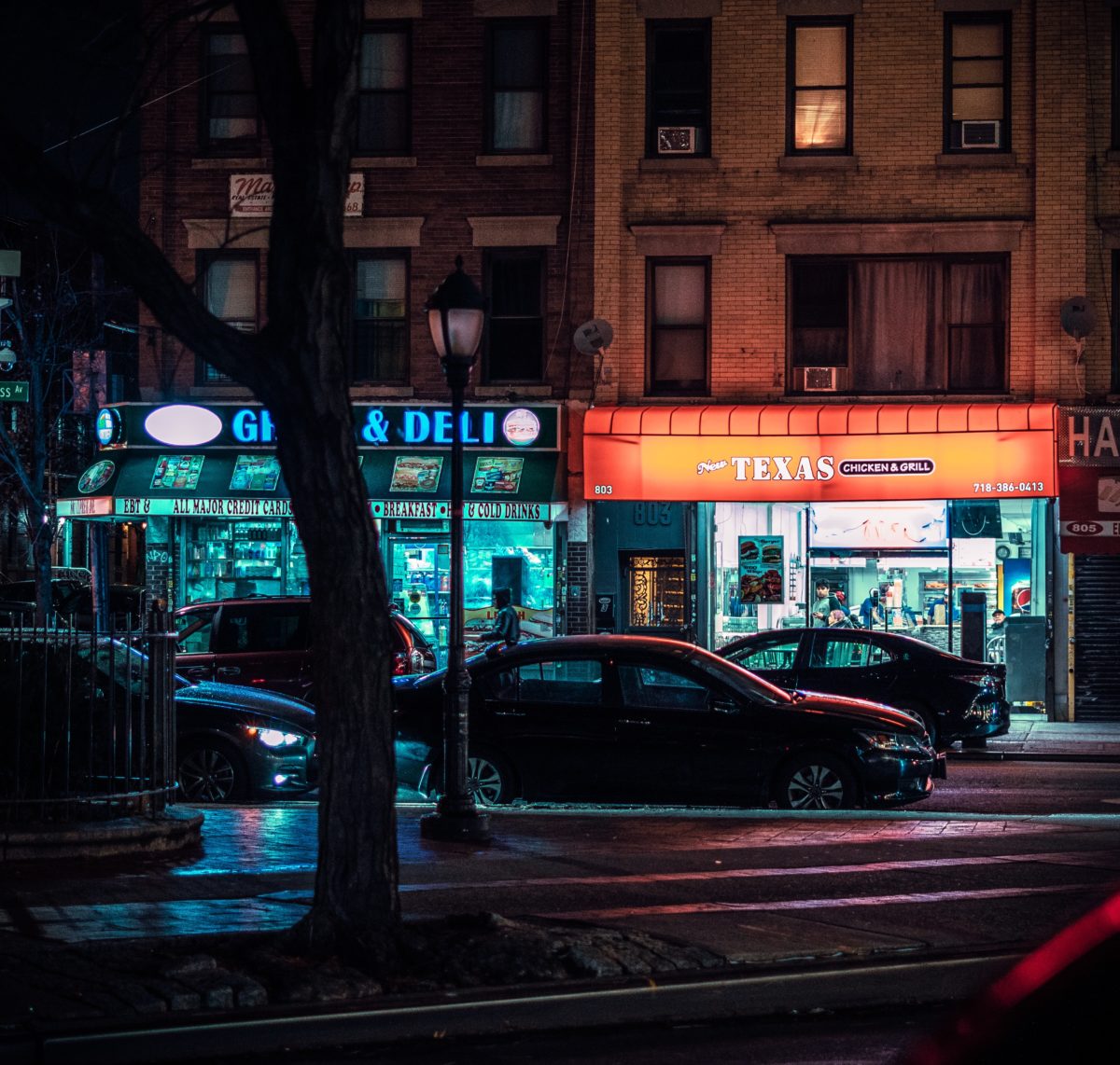 two store fronts lit by their signs at night