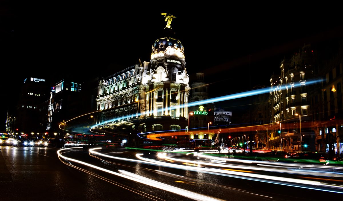 timelapse image of cars whirling by a lit up old building at night