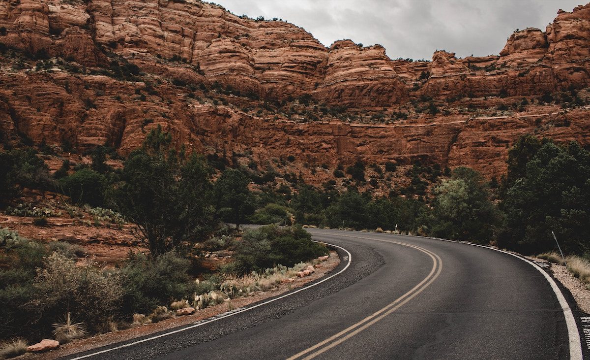 high way curving through tall red rock formations