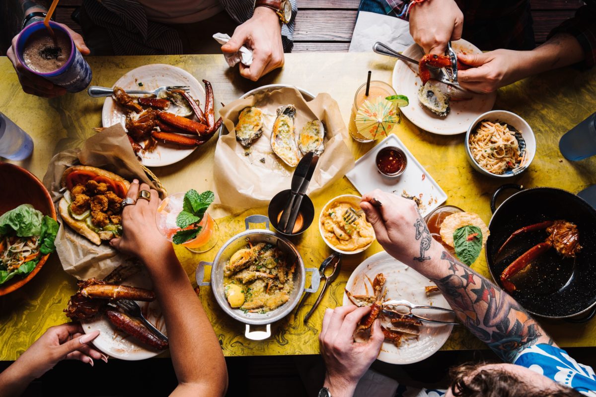 people's hands reaching for food on a yellow table