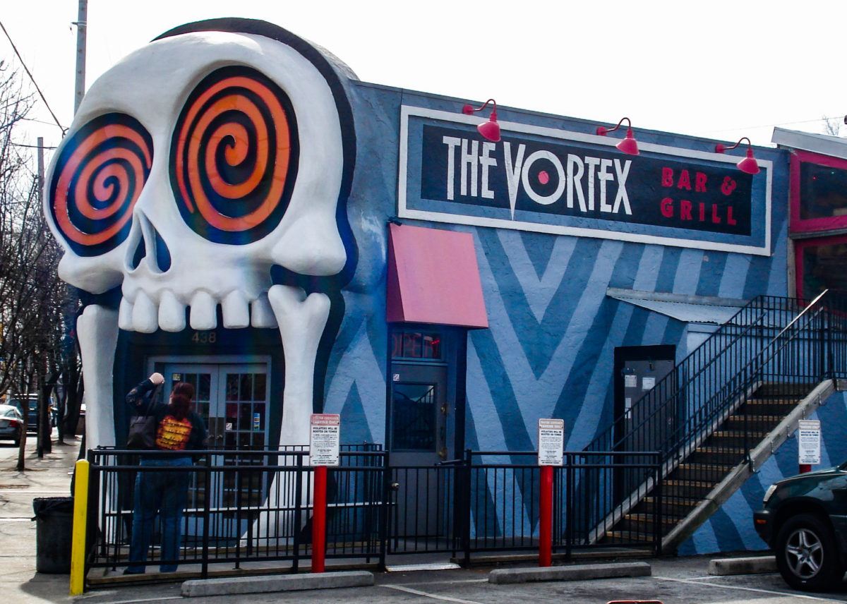 a blue building with a giant skull with swirling eyes as a door