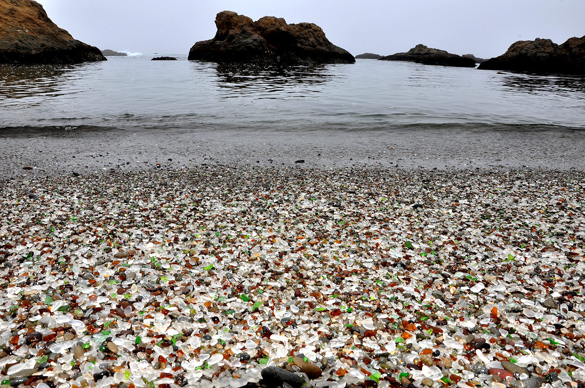 a foggy beach covered in colorful stones