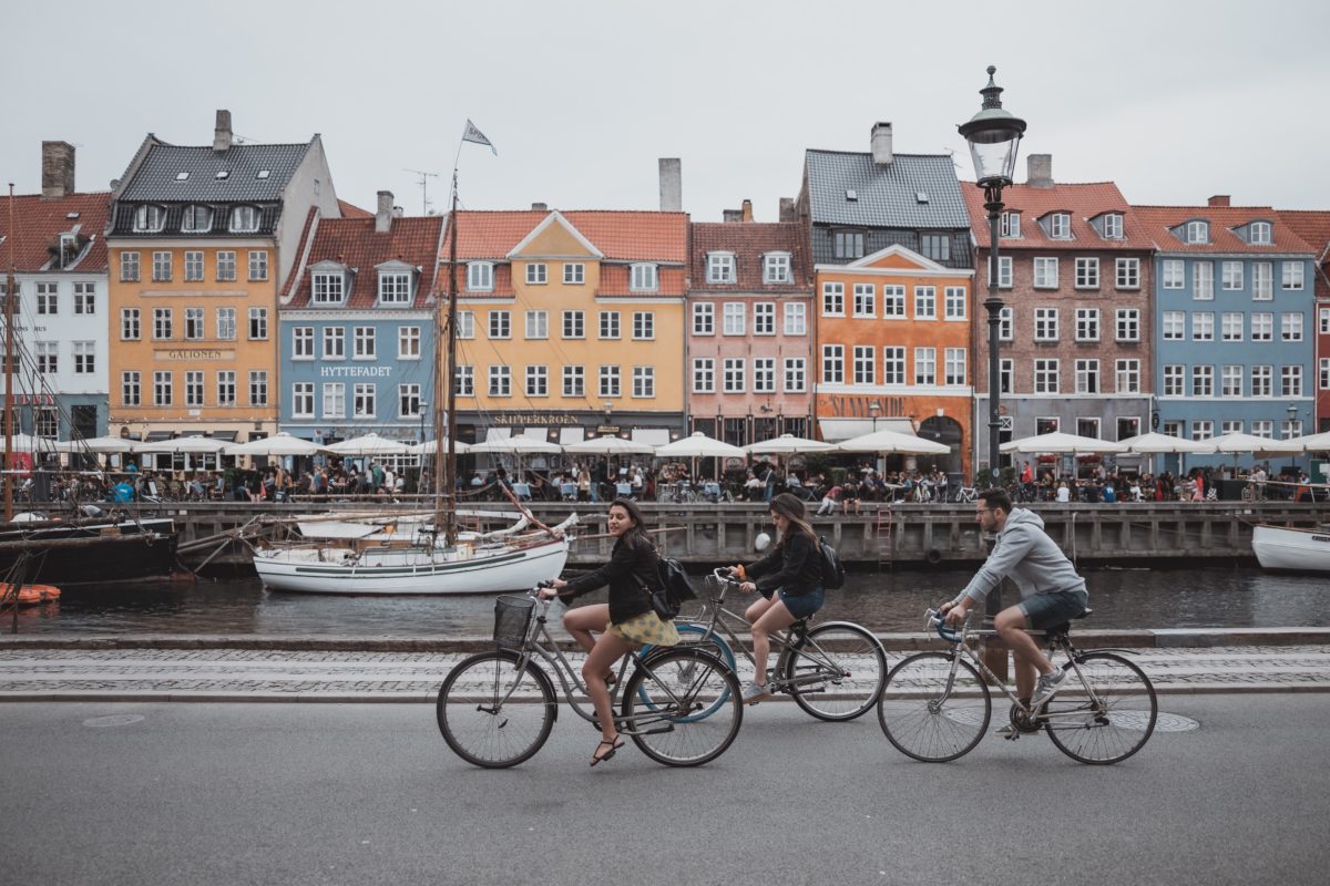 people riding bikes down a canal lined with colorful houses