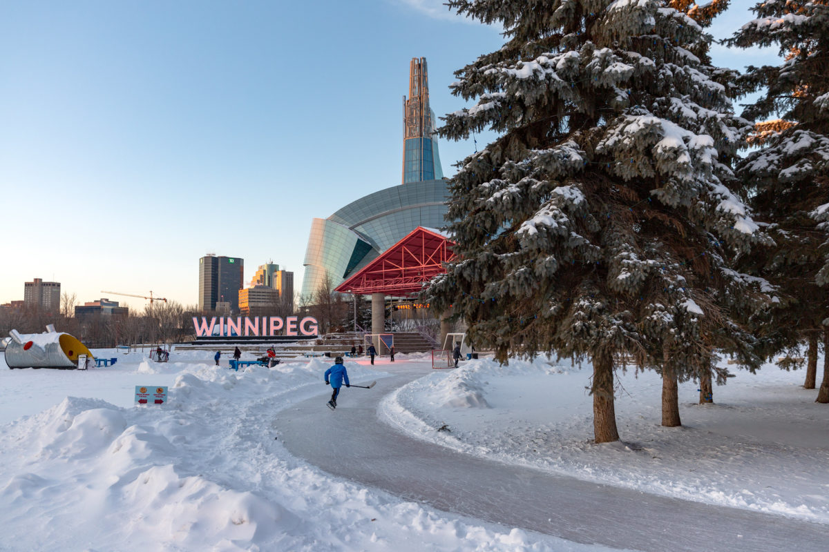 a person skates along a path in the snow with a large sign reading Winnipeg in the background