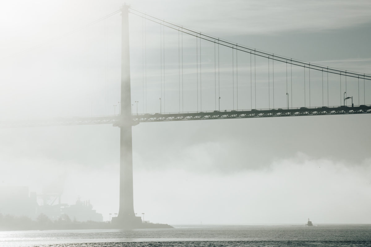 a large bridge over a body of water in the fog