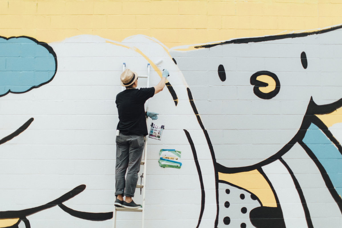 a man in a hat painting a mural