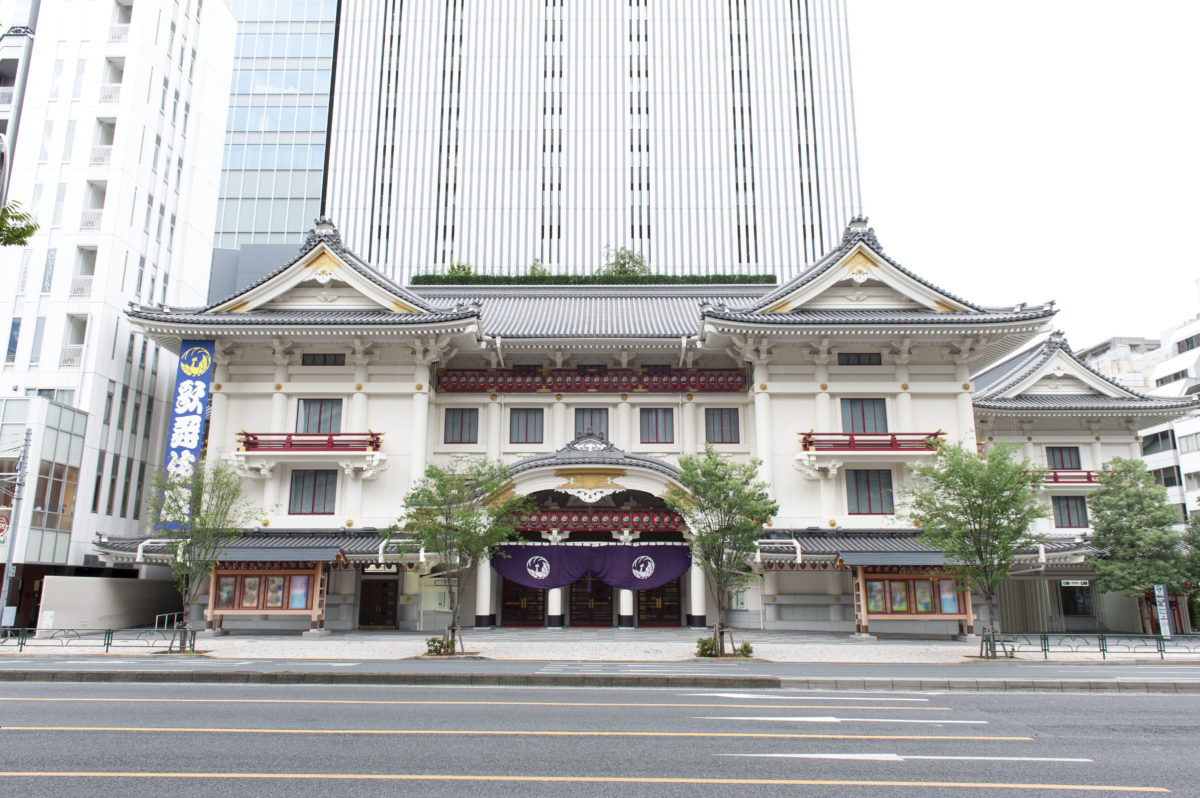 a large, Japanese temple-like theatre in front of a skyscraper on a sunny day