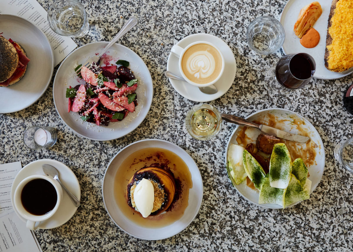 a spread of breakfast foods including pancakes, coffee, and fruit