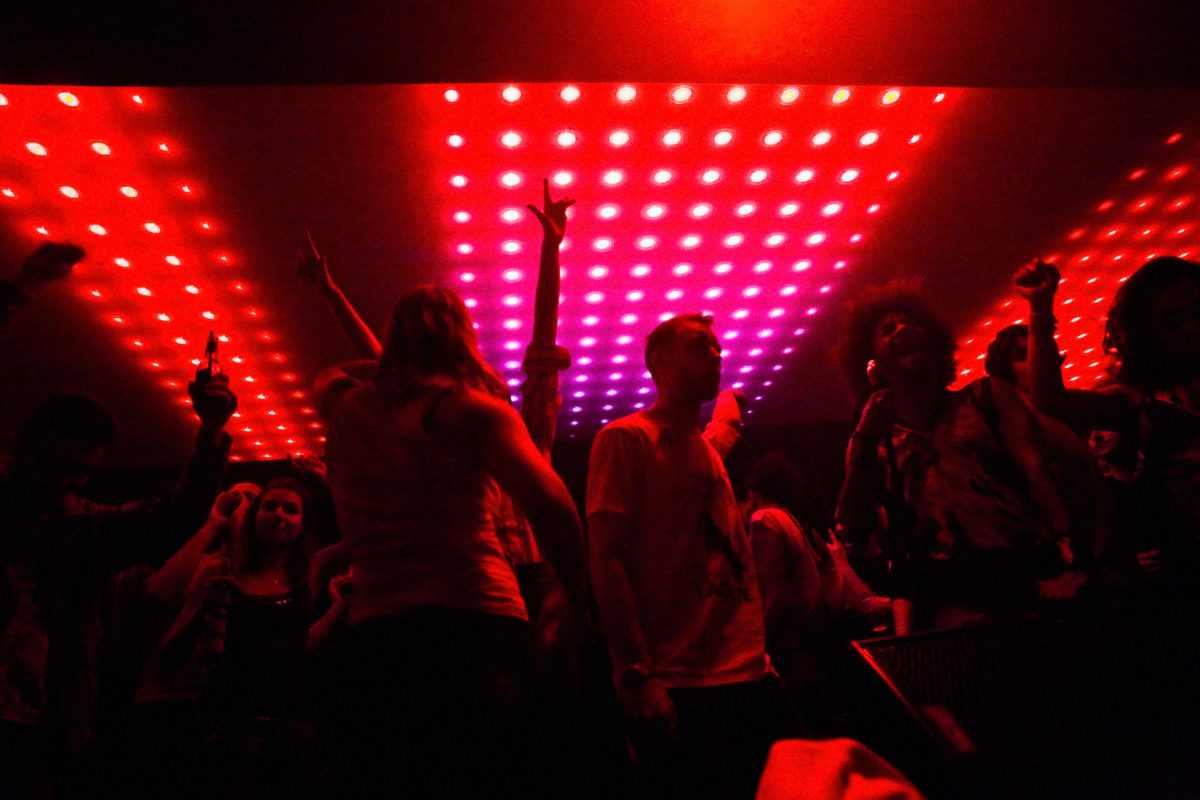 people dancing in a dark nightclub illuminated by red lights