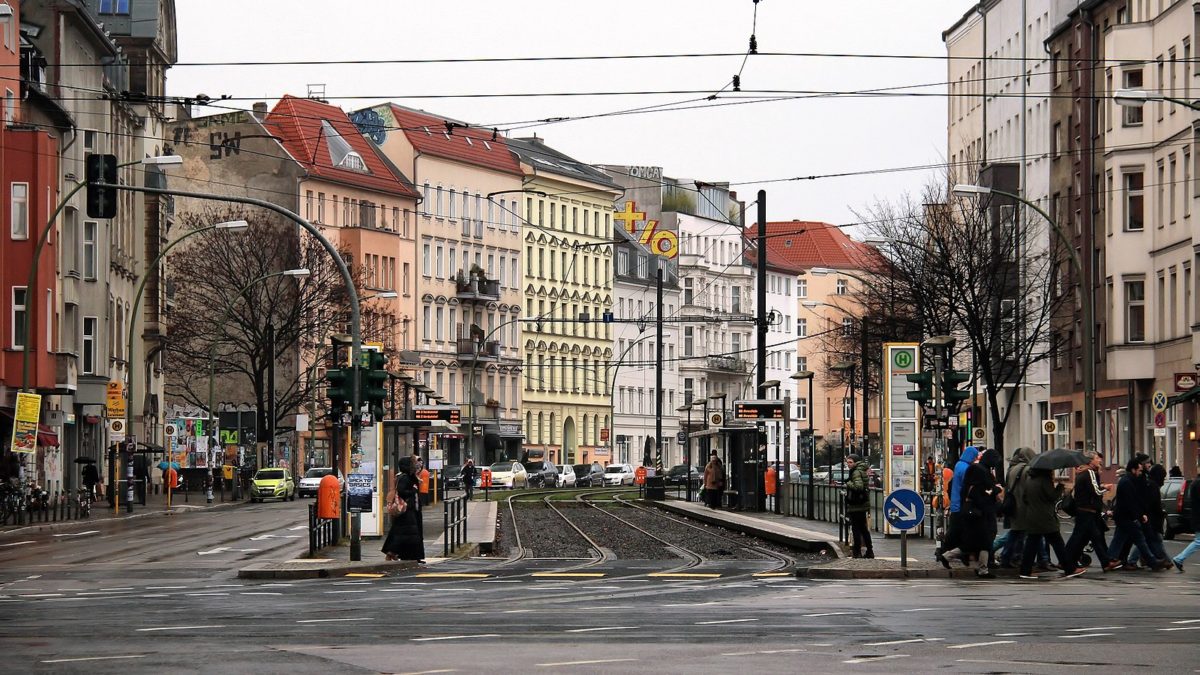 a colorful city block with a tram line running through it on a cloudy day