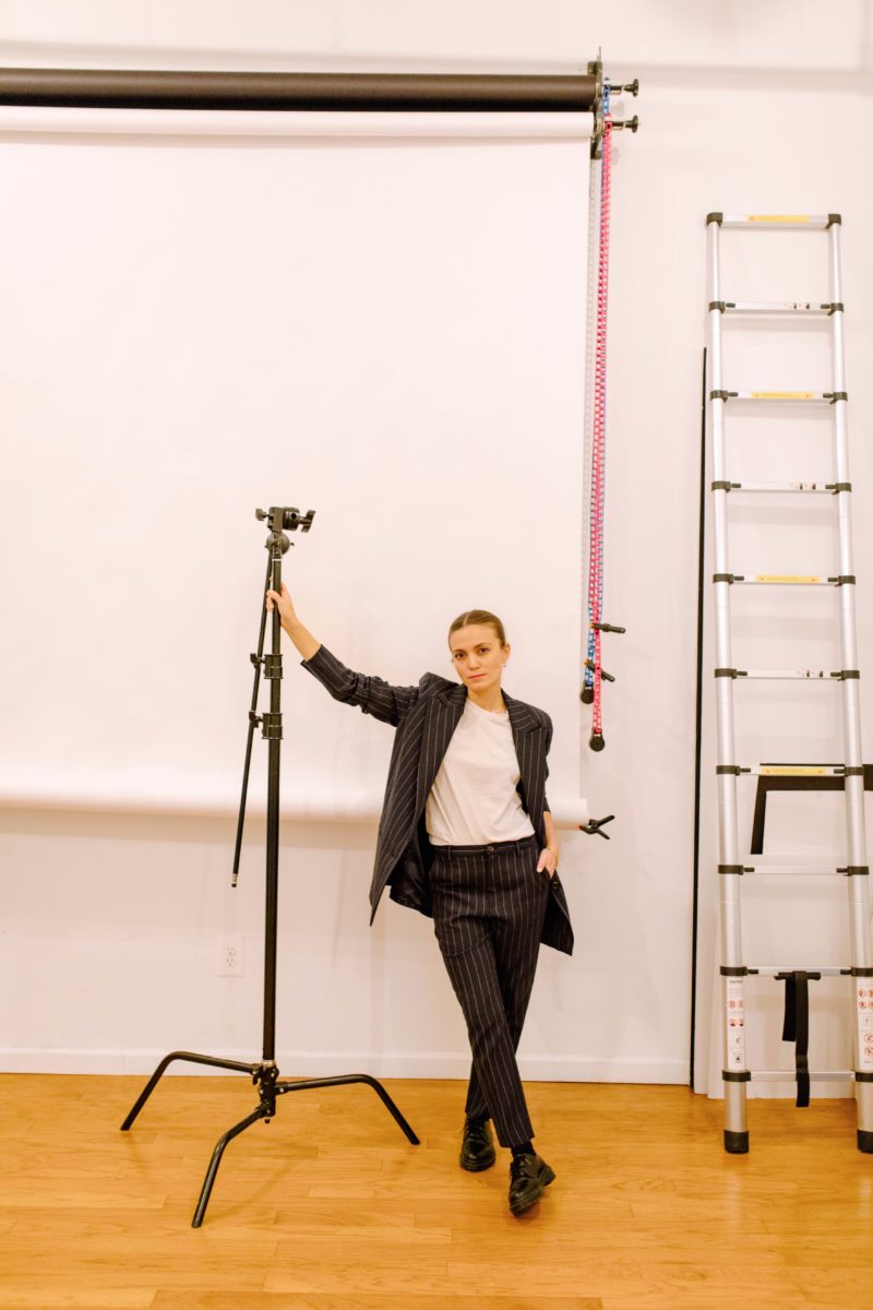 a woman in a suit leans on a lighting tool