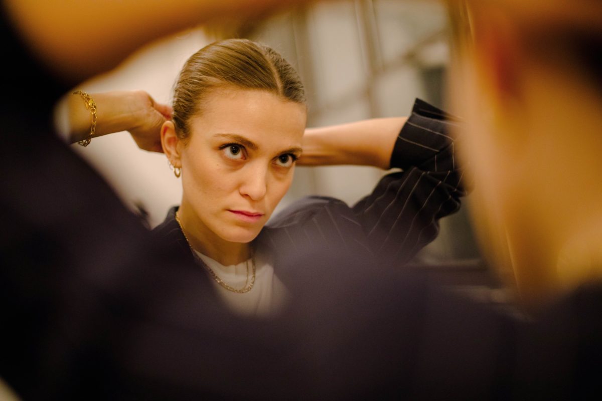 a woman ties her hair in a bun in the mirror