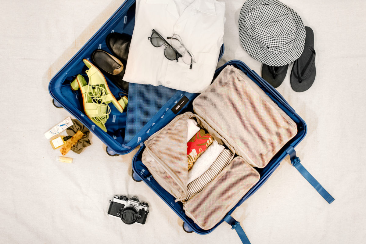 an open suitcase filled with packing cubes, clothes, and accessories