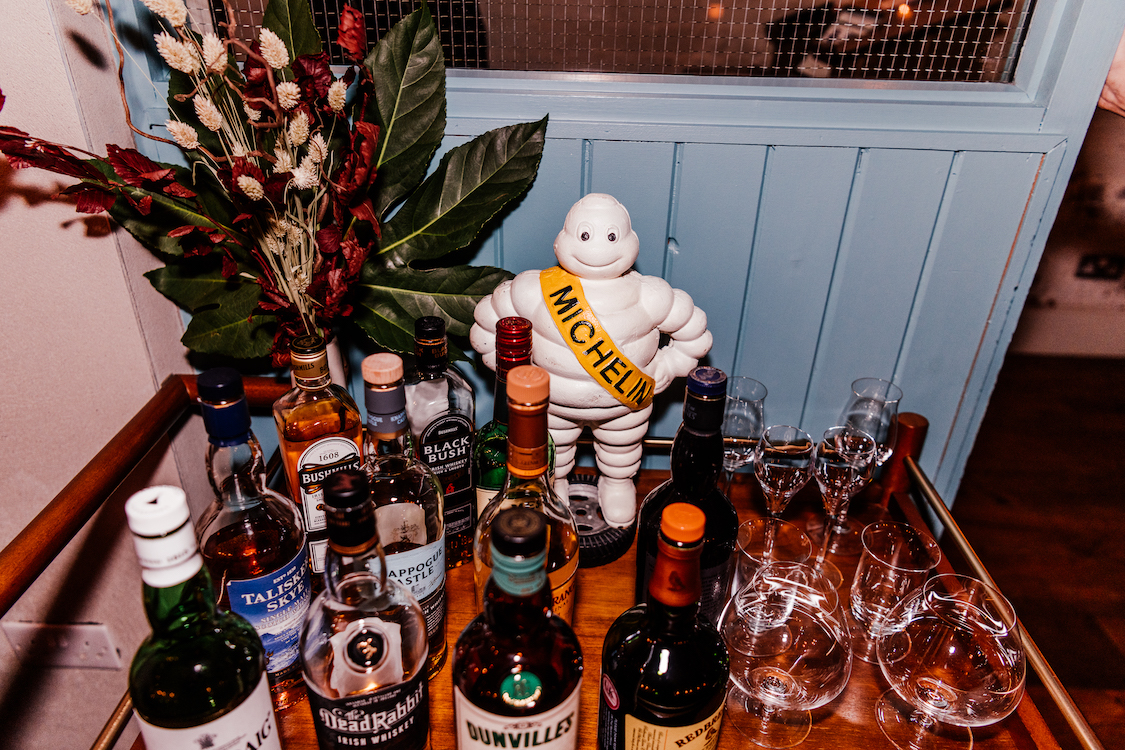 a Michelin man on a tray amongst various bottles of spirits and glasses