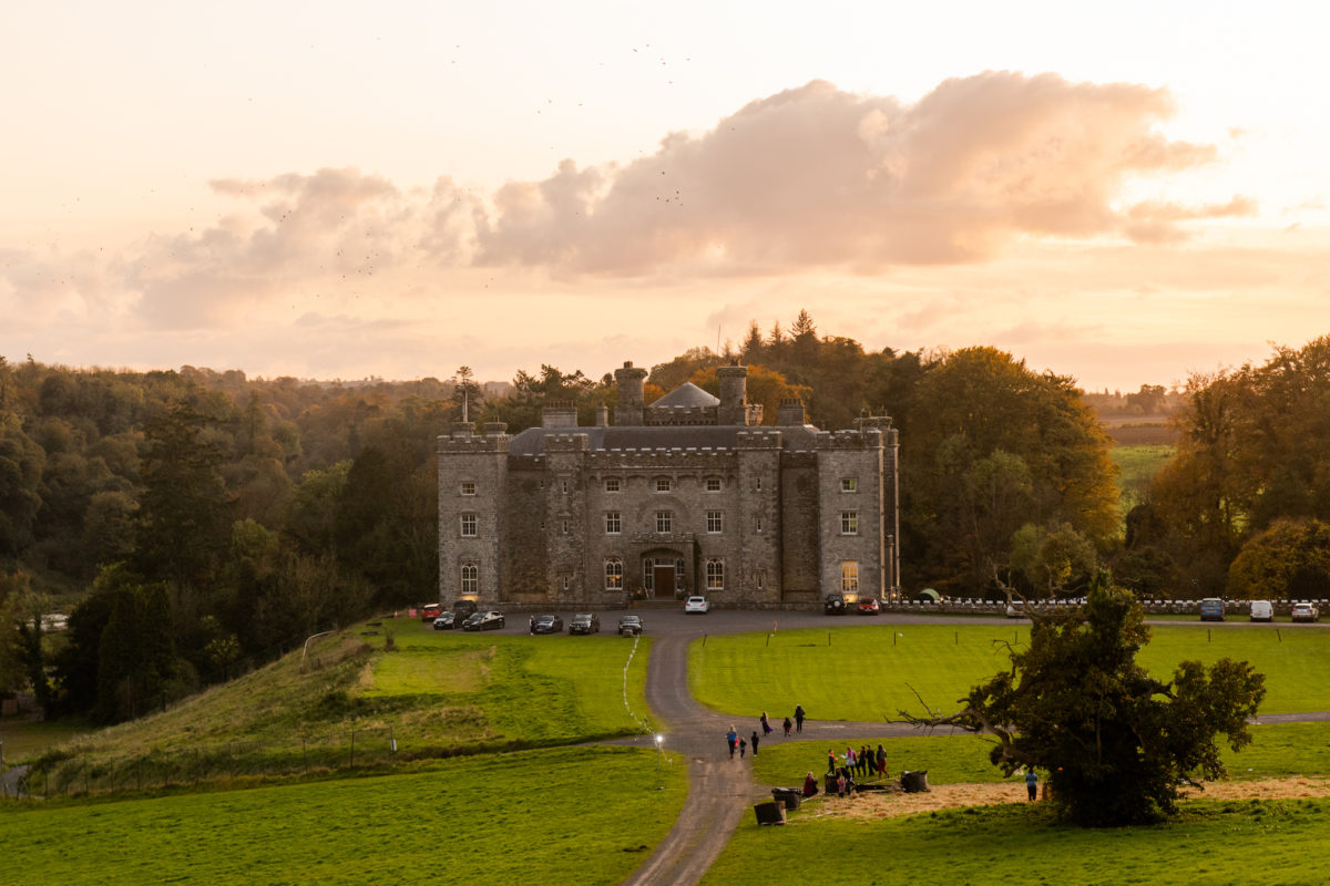 a large castle in the middle of a green field at sunset