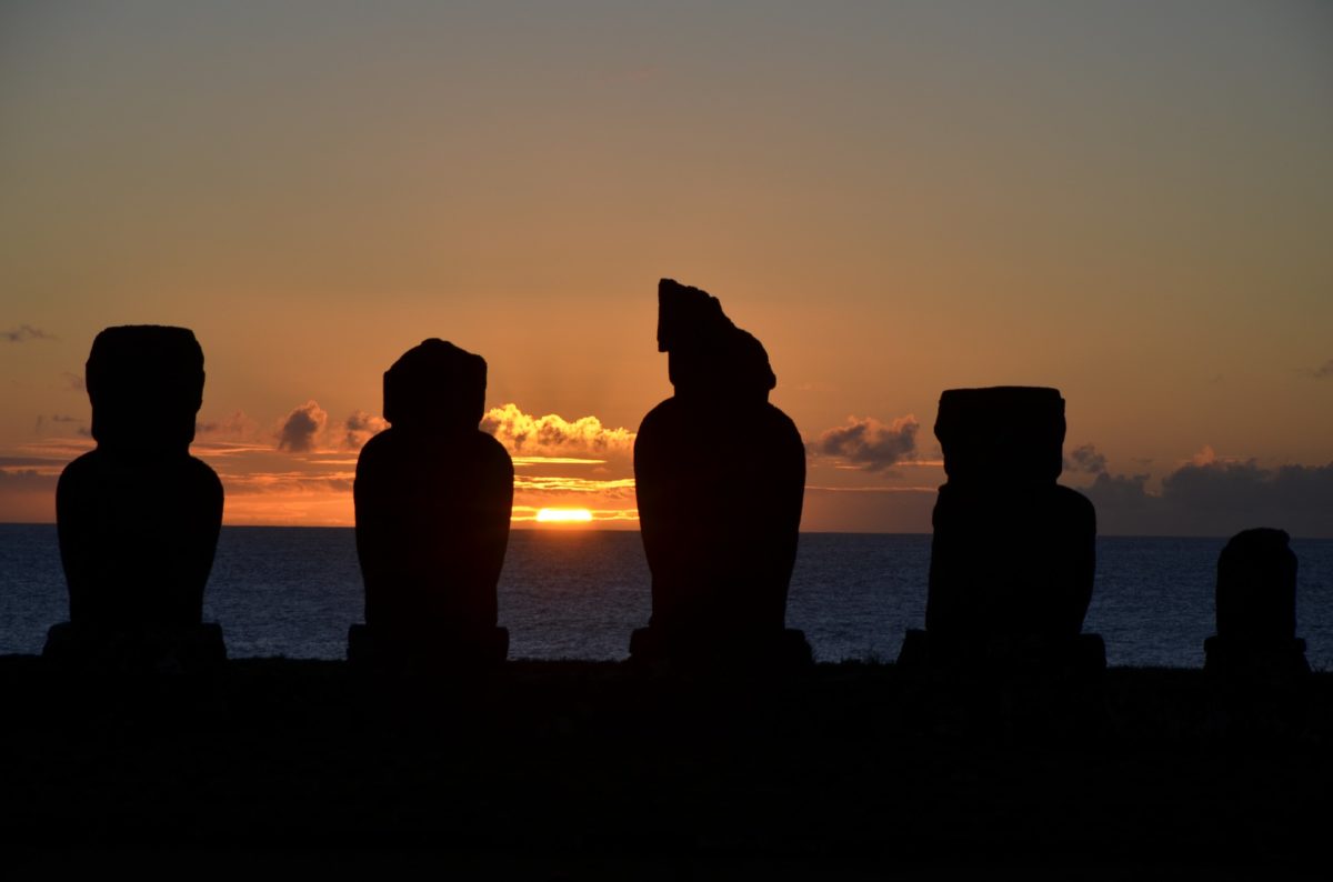 the silhouettes of large stone heads at sunset