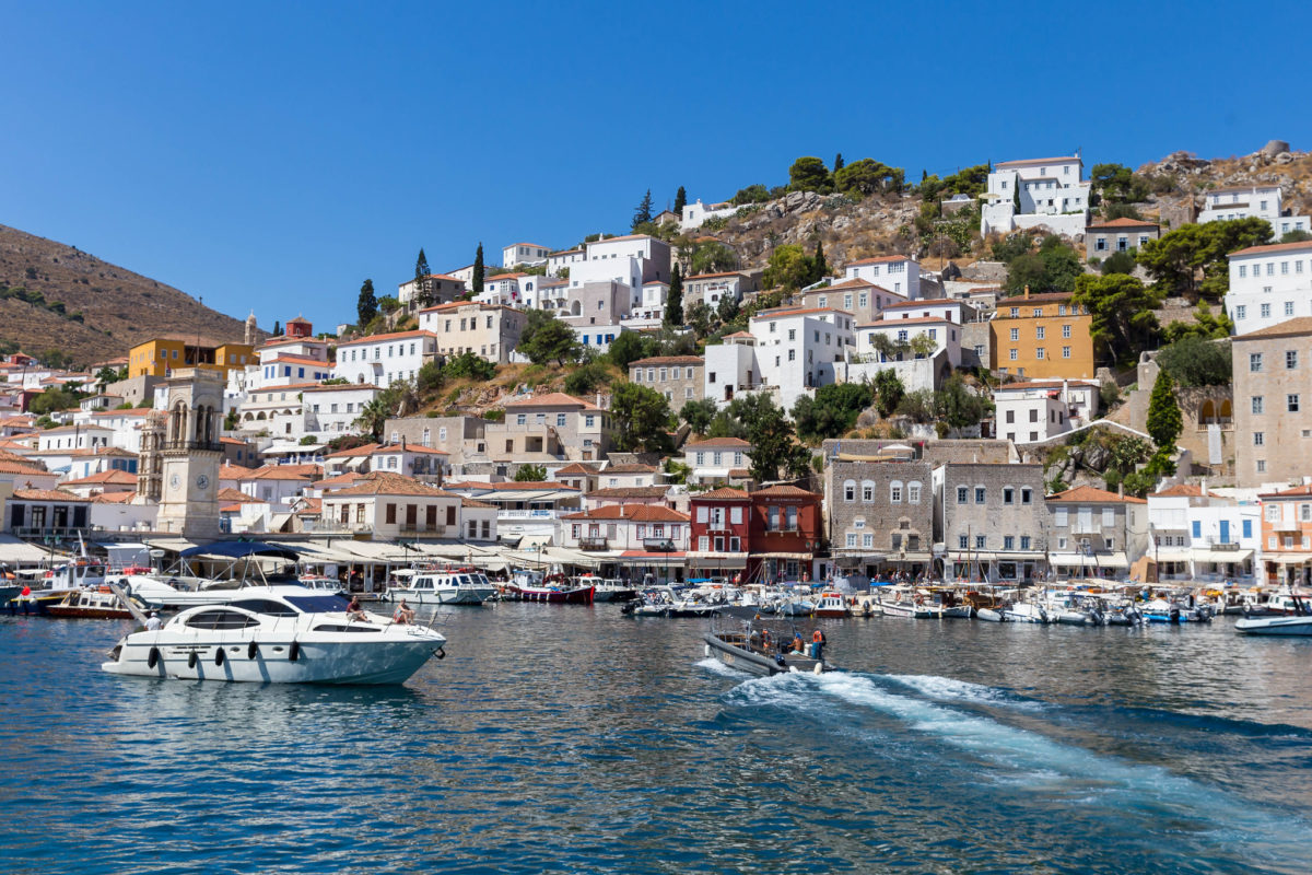 a boat sailing past a seaside town on a hill