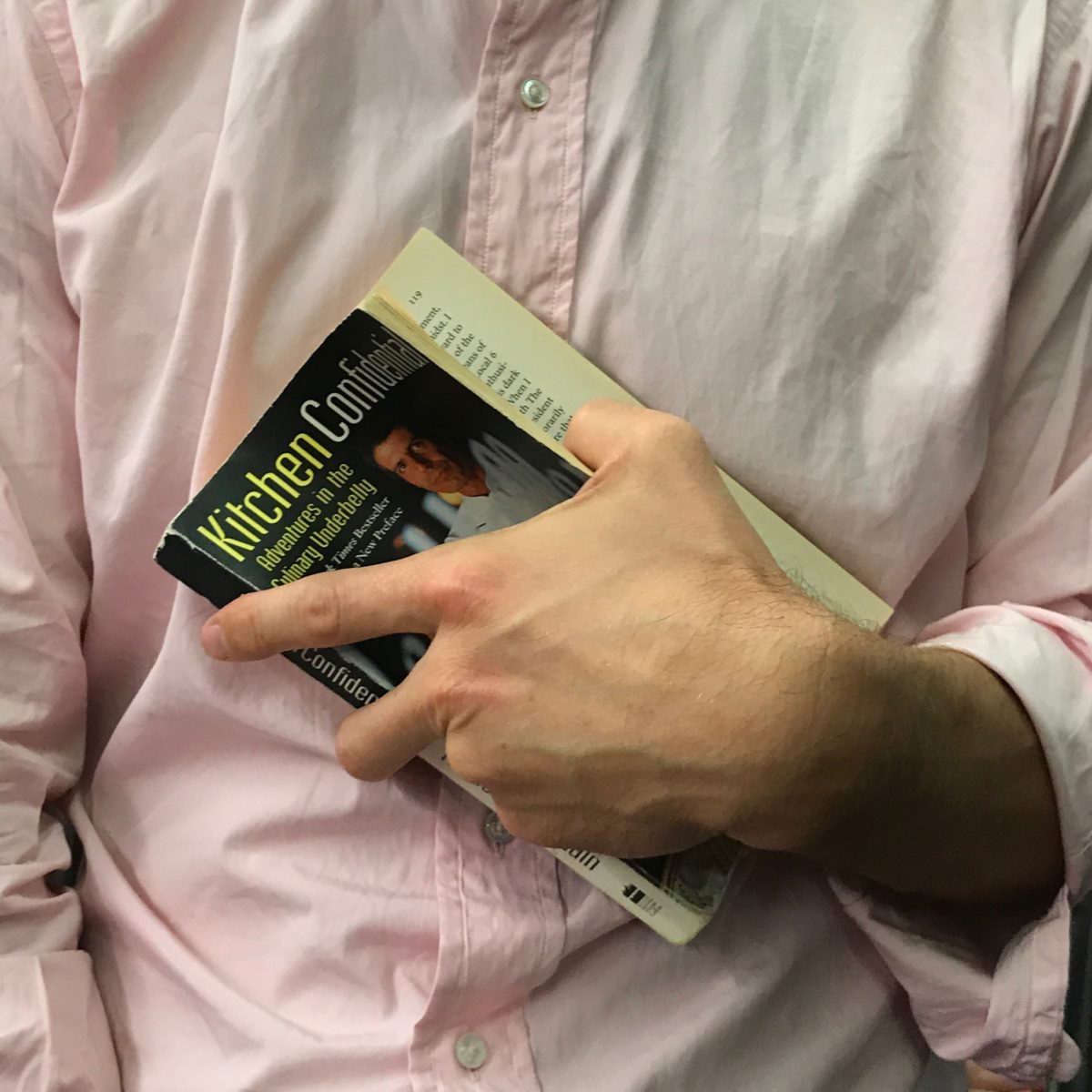 a person's hand holding a book against their chest