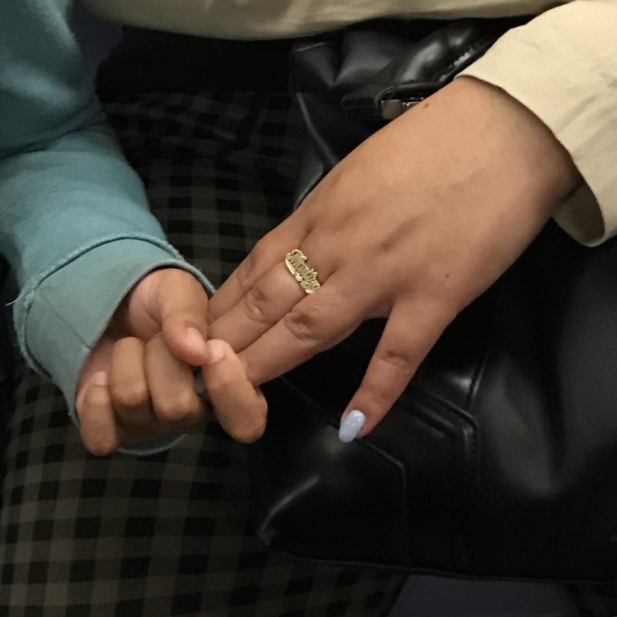 a child's hand grasping their mother's jeweled hand