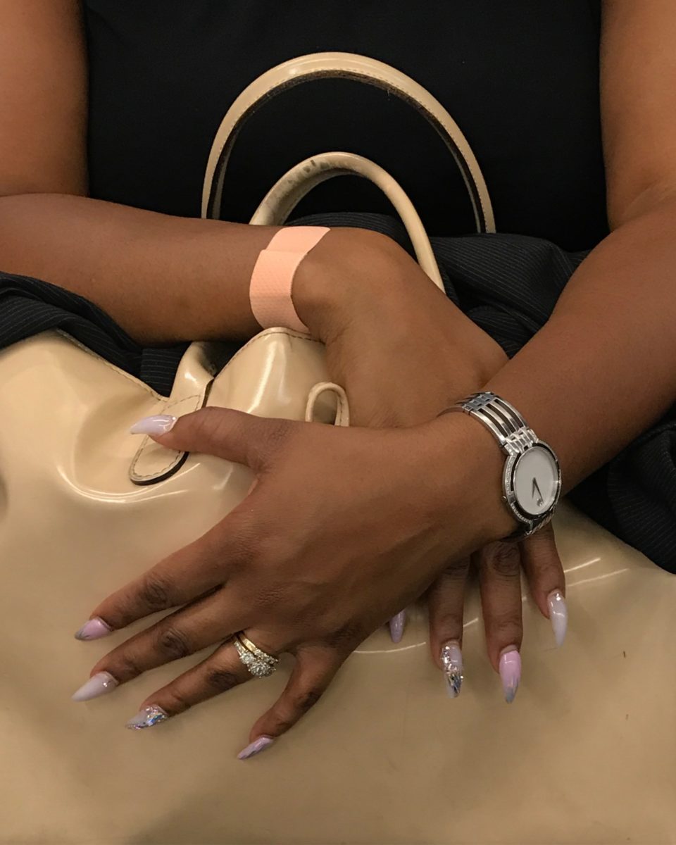 hands with long decorative nails grasping a purse