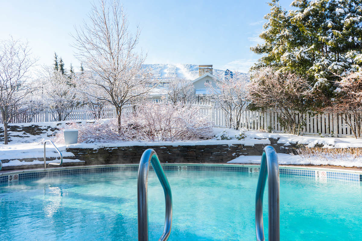 chlorine pool overlooking a snowy mountain peak through the trees