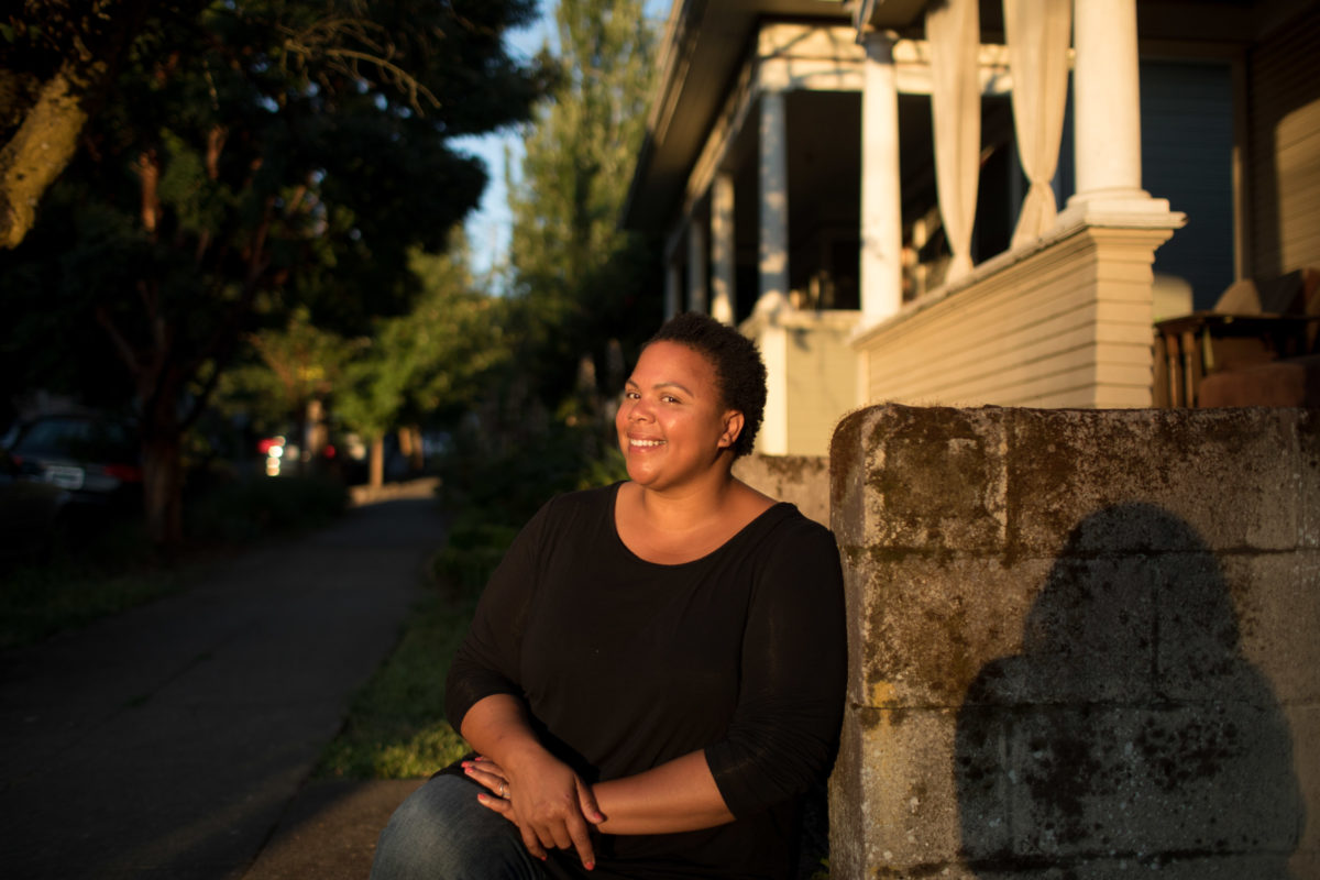 a woman smiling on a neighborhood block on a sunny day