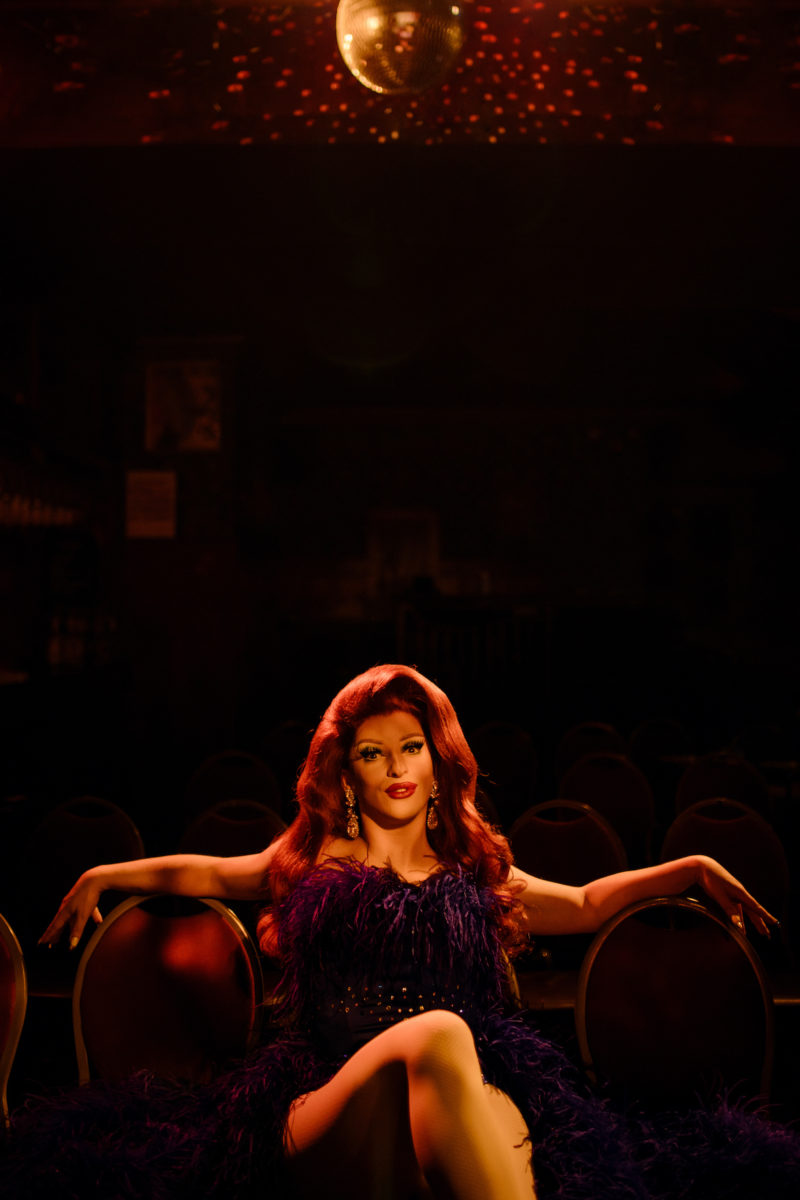 a drag queen lounging in theatre seats