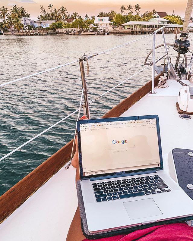 a laptop open to the Google homepage sitting on the cockpit of a sailboat