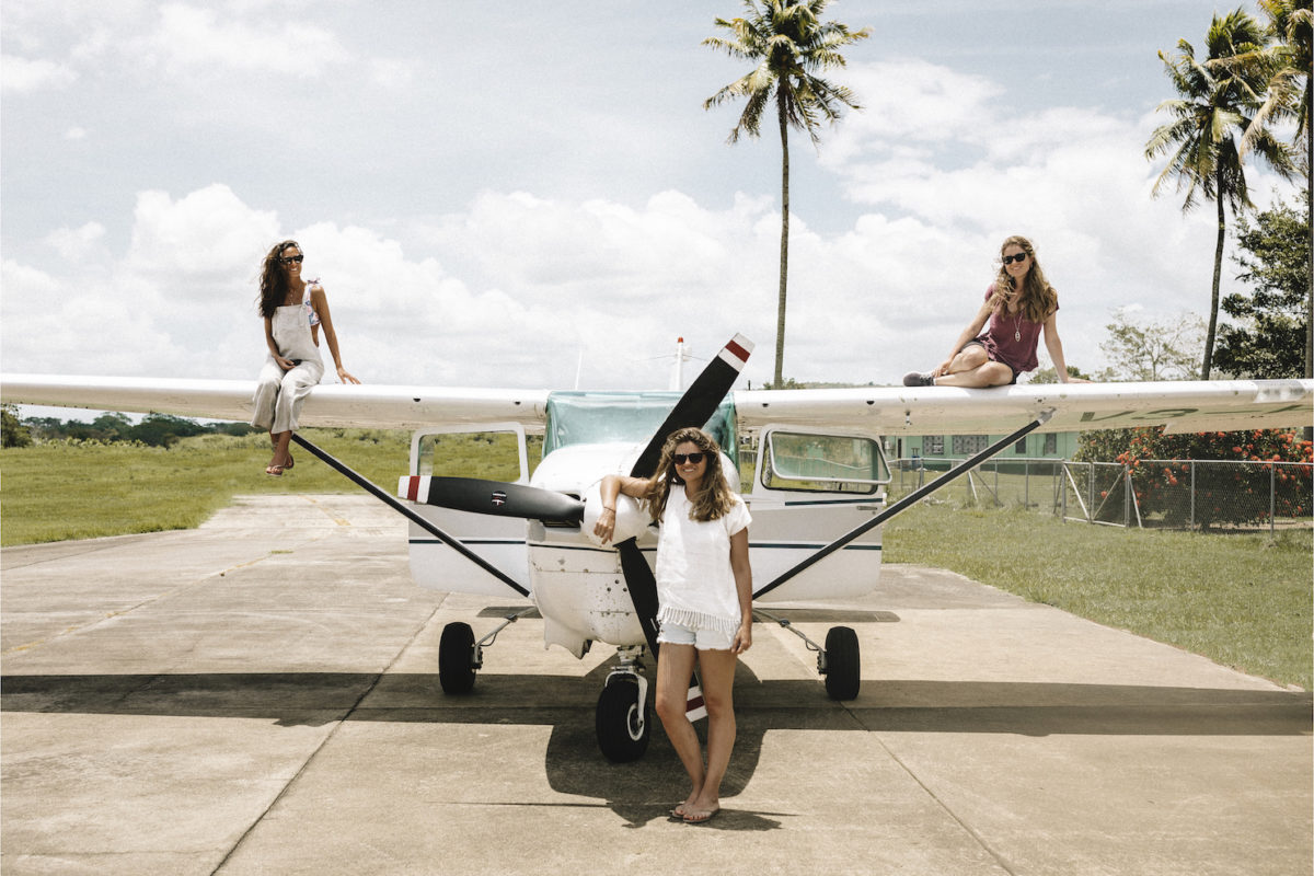 women posing on top and in front of a small airplane