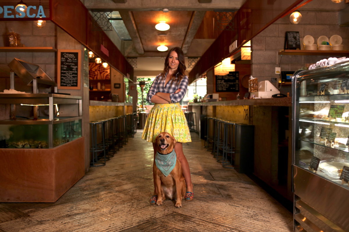 a woman poses with a dog in a food market