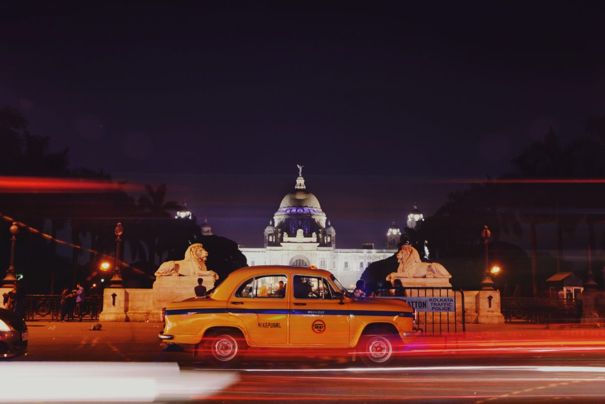 Yellow taxi passes government building in Kolkata, India.