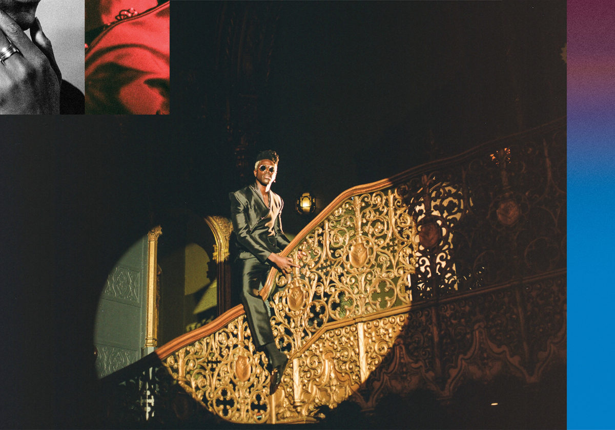 Moses Sumney straddling the railing of an ornate staircase with a circular spotlight shining on him