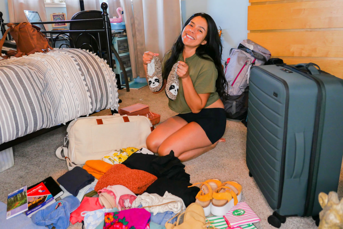 a woman smiles in front of unpacked suitcases