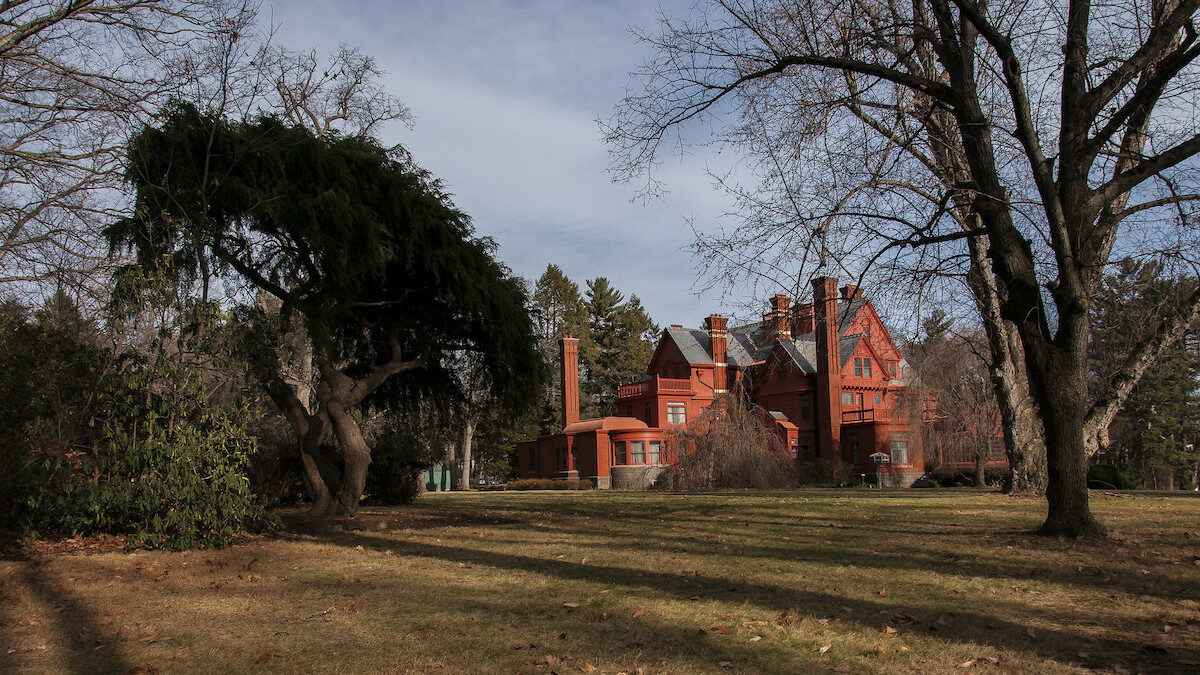 a large, old red house on a green lawn