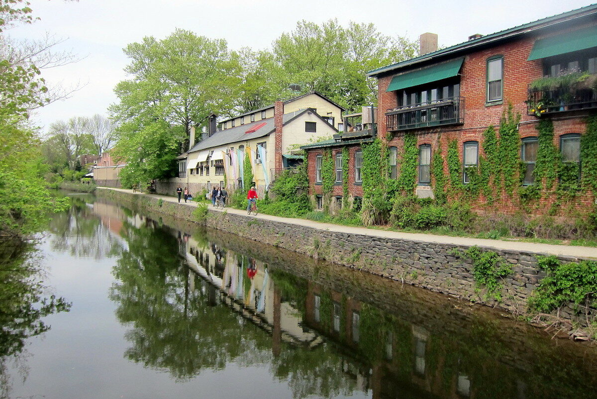 bikers along a canal lined with historic buildings